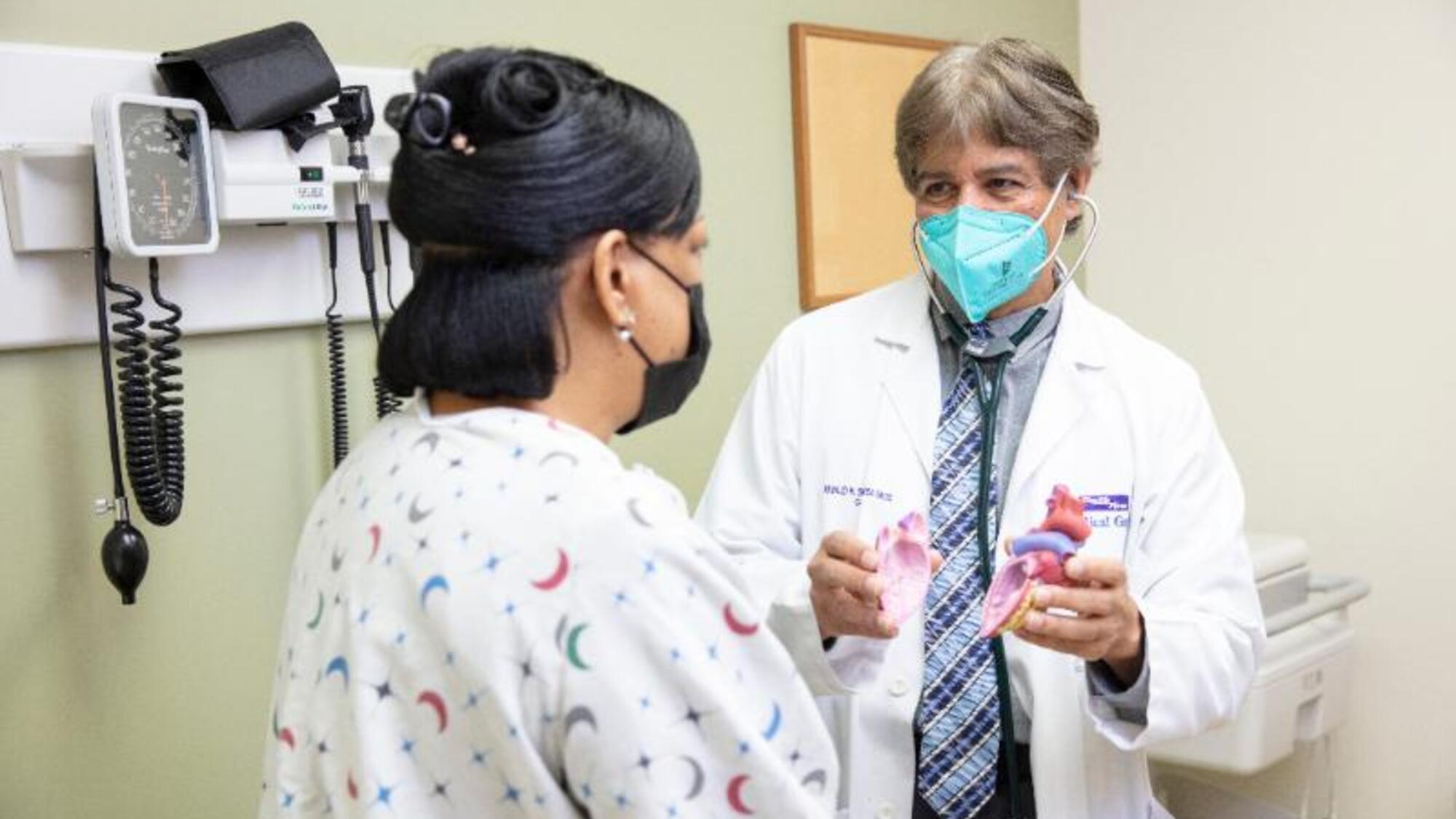 Doctor and patient wearing masks while discussing heart risks prevention 